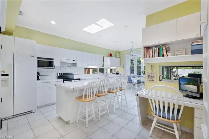 Kitchen with white cabinetry, white refrigerator with ice dispenser, electric stove, and stainless steel microwave