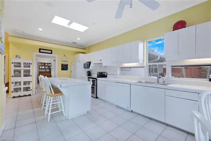 Kitchen featuring appliances with stainless steel finishes, sink, a center island, white cabinetry, and ceiling fan