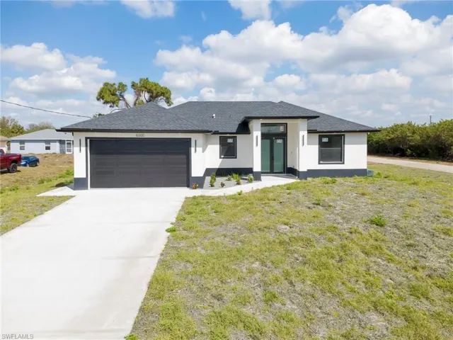 Prairie-style home with stucco siding, an attached garage, a front lawn, and concrete driveway