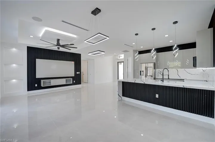 Kitchen with light stone countertops, stainless steel refrigerator with ice dispenser, modern cabinets, pendant lighting, and a kitchen bar