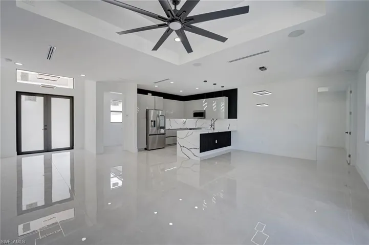 Kitchen featuring a peninsula, stainless steel appliances, a raised ceiling, open floor plan, and decorative light fixtures