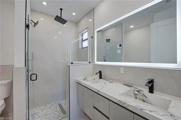 Full bath with a stall shower, double vanity, and recessed lighting