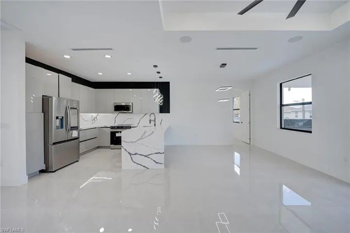 Kitchen featuring stainless steel appliances, pendant lighting, light stone countertops, modern cabinets, and tasteful backsplash