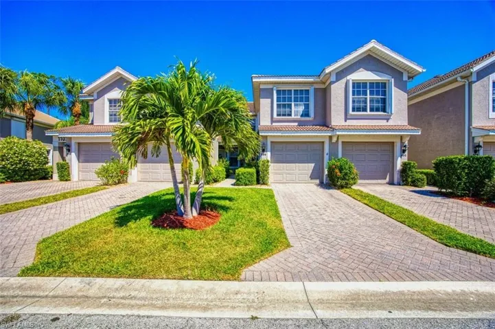 Traditional-style house featuring stucco siding, an attached garage, a tile roof, decorative driveway, and a front yard