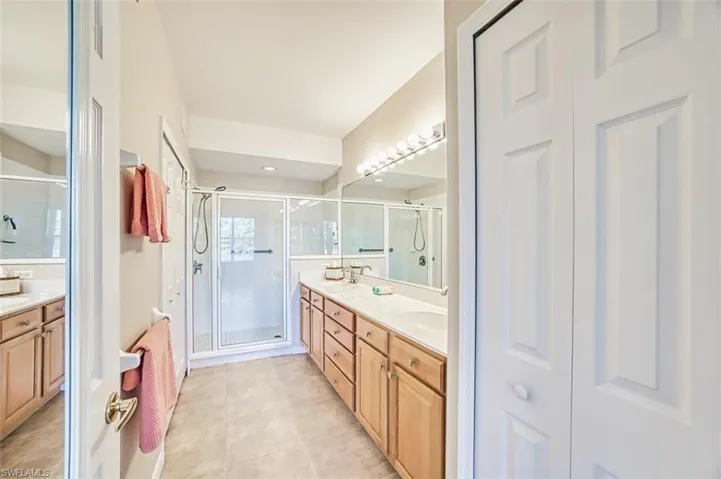 Full bath with double vanity, a stall shower, a closet, and light tile patterned flooring