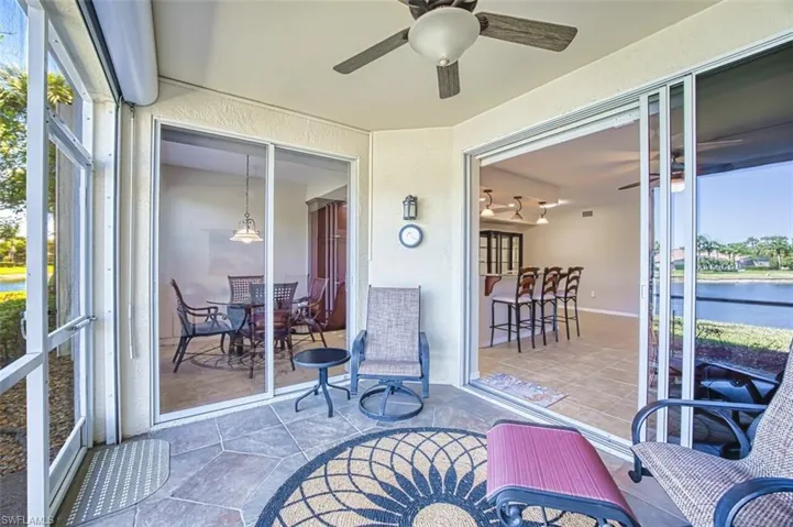 Sunroom featuring a water view, a ceiling fan, and a patio