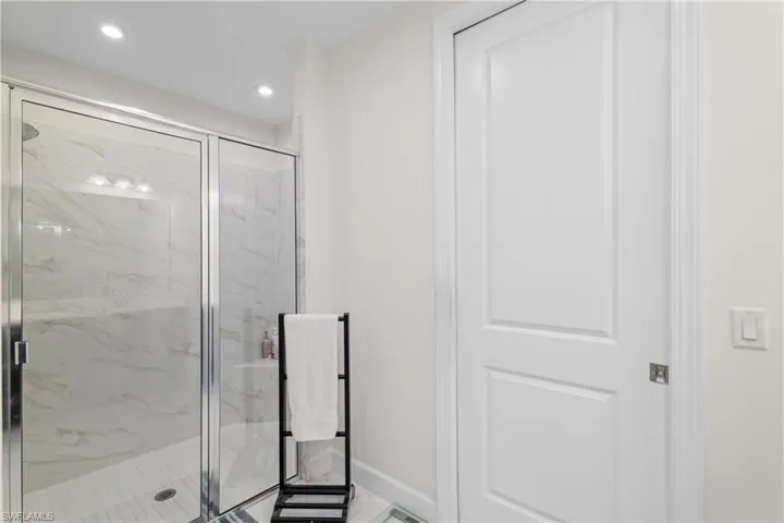 Full bath with light marble finish floors, a marble finish shower, and recessed lighting