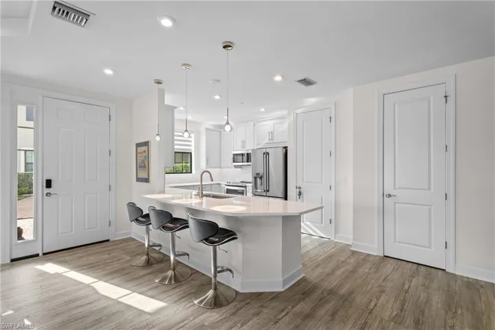 Kitchen with white cabinets, decorative light fixtures, a kitchen breakfast bar, stainless steel appliances, and a peninsula