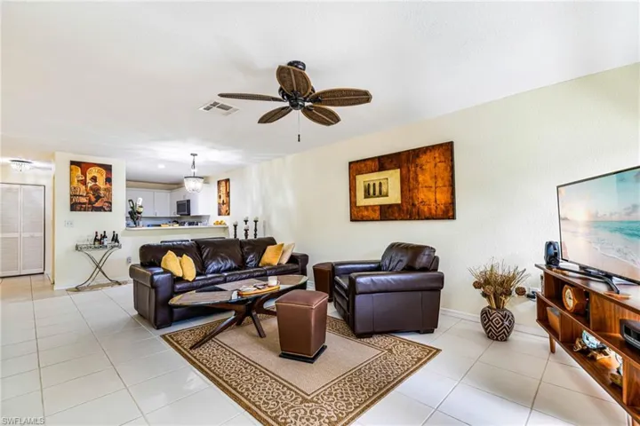 Living area featuring light tile patterned floors and ceiling fan