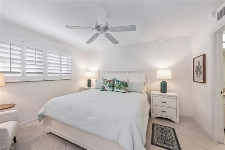 Bedroom with ceiling fan, light tile patterned floors, and ornamental molding