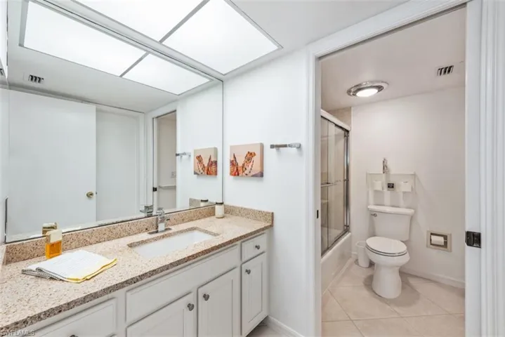 Full bathroom featuring tile patterned flooring, vanity, bath / shower combo with glass door.