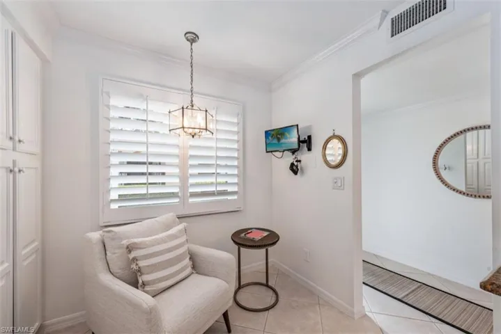 Sitting area with an inviting chandelier, ornamental molding, and light tile patterned flooring