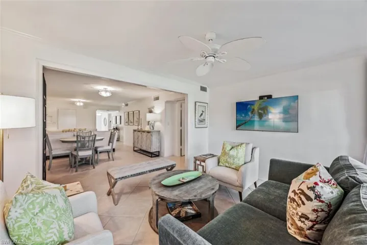 Tiled living room with ceiling fan and ornamental molding