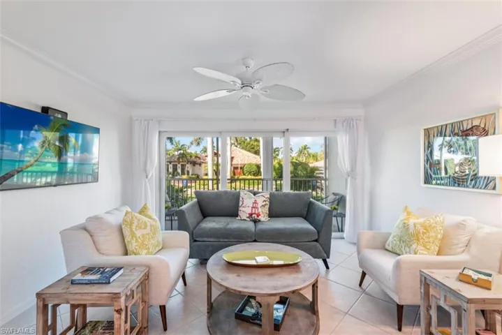 Living room with ceiling fan, light tile patterned floors, and crown molding