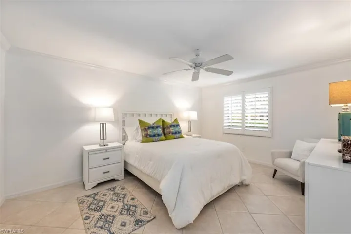 Bedroom featuring ceiling fan, crown molding, and light tile patterned floors