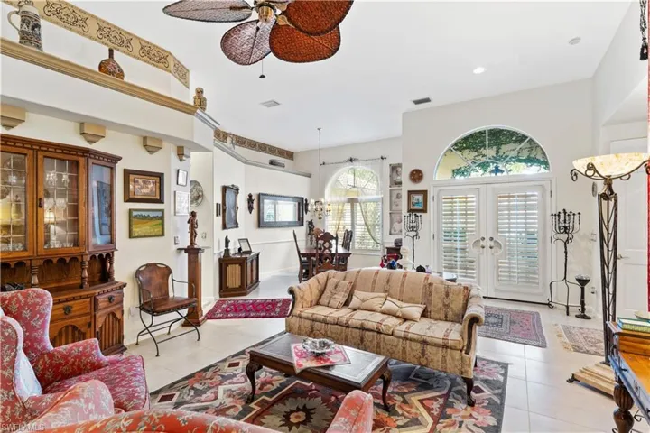 Tiled living room with ceiling fan and french doors