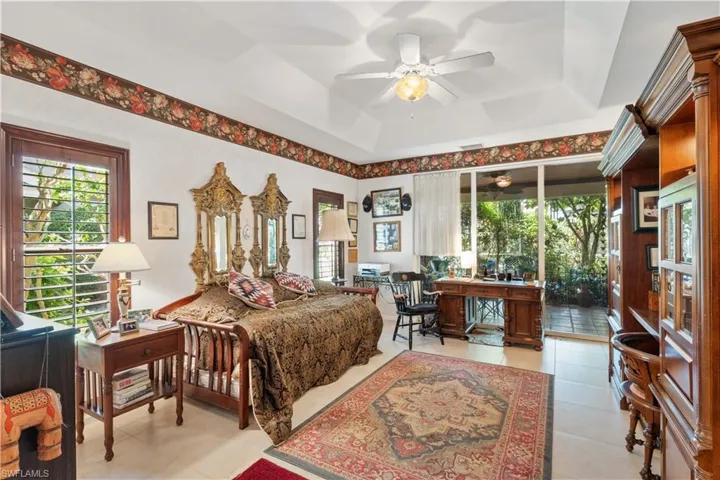 Bedroom with tile flooring, access to exterior, ceiling fan, and a raised ceiling