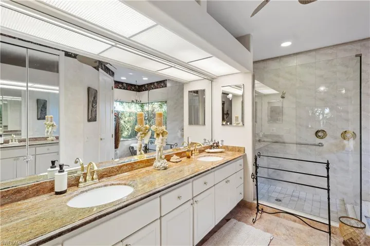 Bathroom featuring dual vanity, walk in shower, ceiling fan, and tile floors