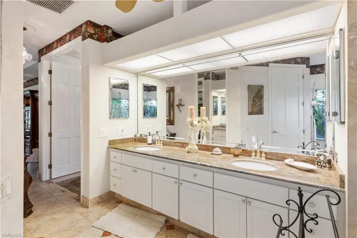 Bathroom with vanity with extensive cabinet space, dual sinks, and tile flooring