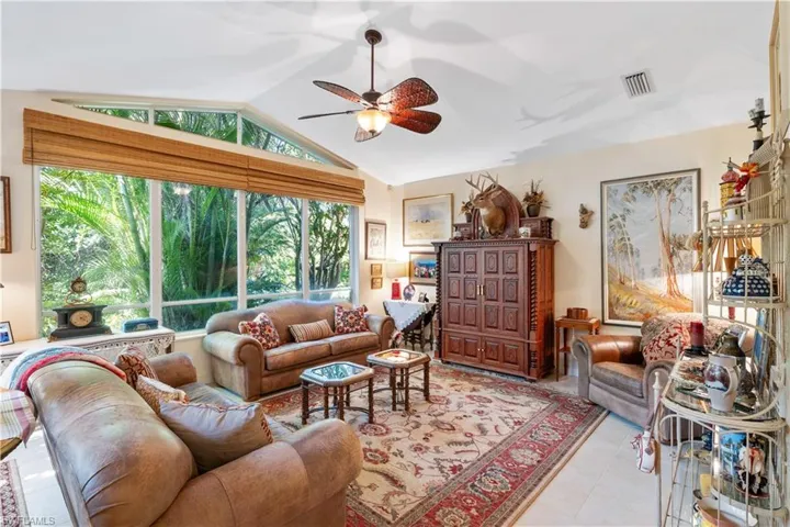 Tiled living room with lofted ceiling and ceiling fan