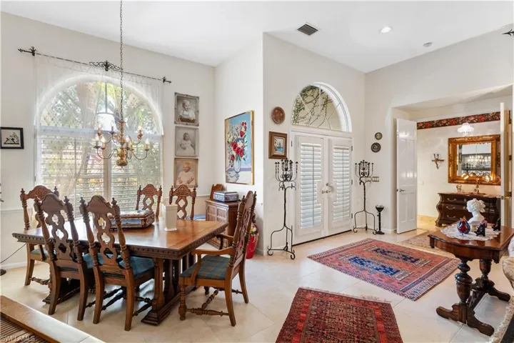 Dining space with french doors, light tile floors, and an inviting chandelier