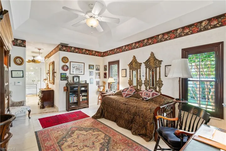 Tiled bedroom featuring ceiling fan and a raised ceiling