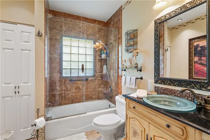 Full bathroom featuring enclosed tub / shower combo, tile flooring, vanity, and toilet