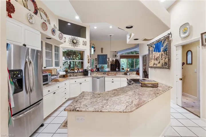 Kitchen featuring white cabinets, light tile flooring, a kitchen island, and stainless steel appliances