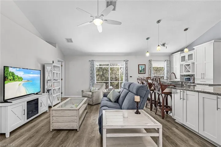 Living area featuring lofted ceiling, a ceiling fan, and dark wood-type flooring