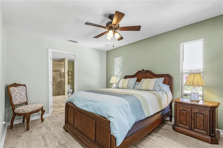 Bedroom with a ceiling fan, light wood-style floors, and connected bathroom