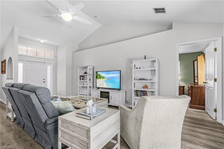 Living room featuring wood finished floors, a ceiling fan, and lofted ceiling