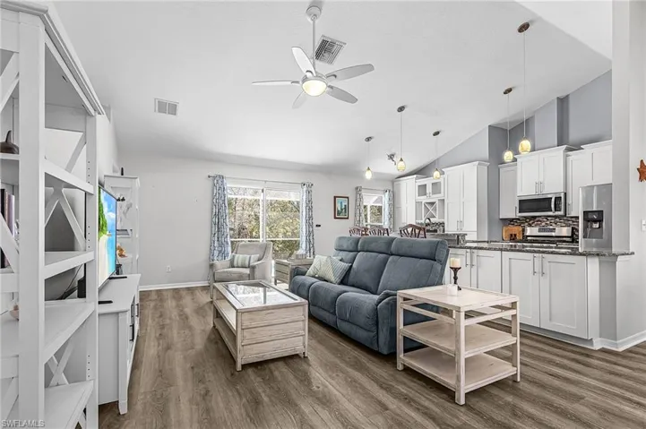Living room featuring lofted ceiling, ceiling fan, and dark wood-style flooring