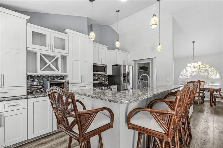 Kitchen featuring quartz countertops, a breakfast bar, white cabinets, stainless steel appliances, and tasteful backsplash