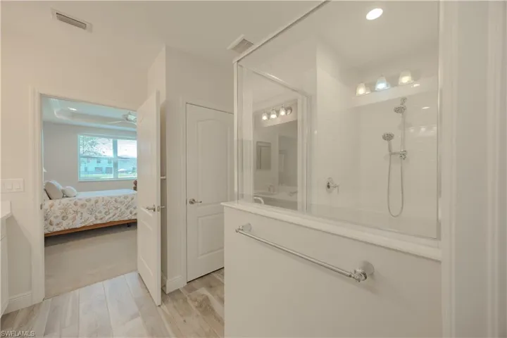 Bathroom featuring ensuite bath, vanity, tiled shower, light wood-style floors, and a ceiling fan
