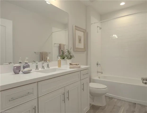 Bathroom with vanity, shower / bath combination, and light wood-style floors
