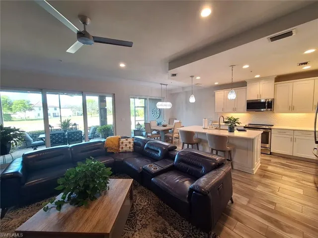 Living room with light wood-type flooring, a ceiling fan, and recessed lighting
