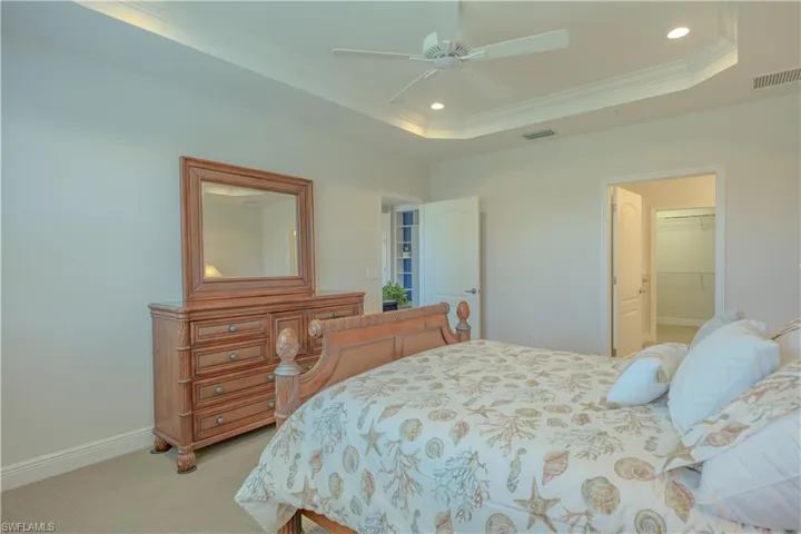 Bedroom with recessed lighting, ornamental molding, a walk in closet, light carpet, and ceiling fan