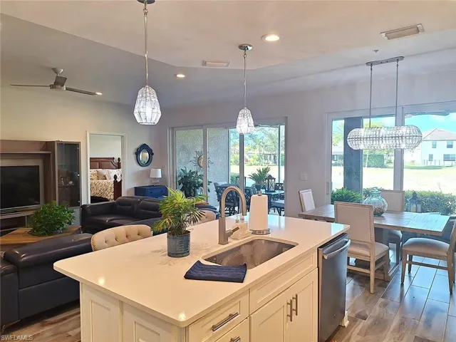 Kitchen with white cabinets, open floor plan, light wood-type flooring, and an island with sink