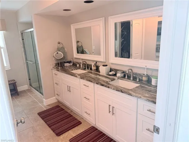 Bathroom with double vanity, a stall shower, and tile patterned floors