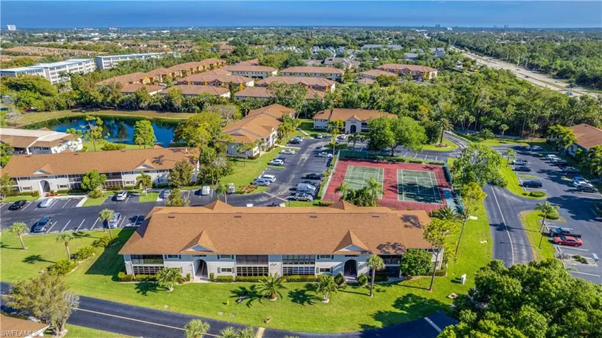 Aerial overview showcasing residential buildings with new(er) roofs, surrounded by mature trees.