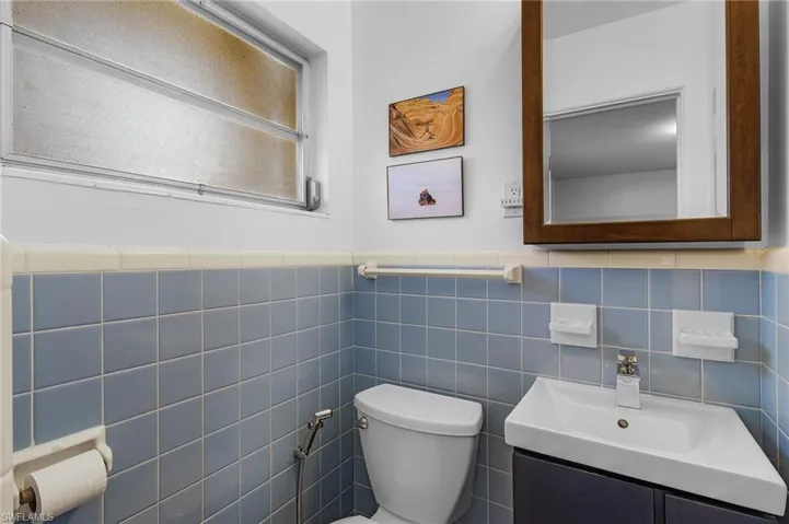 Half bath featuring a wainscoted wall, toilet, and vanity
