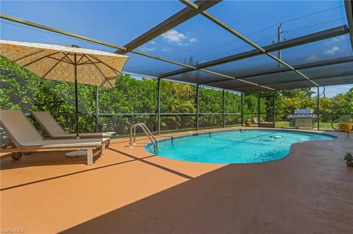 Pool with a lanai, grilling area, and a patio