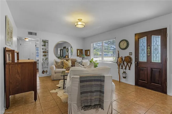 Living area featuring light tile patterned floors, visible vents, and built in shelves