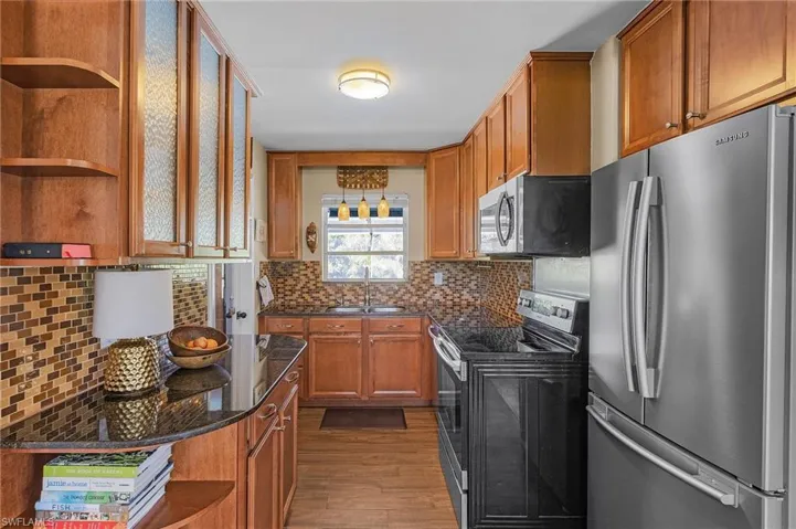 Kitchen featuring a sink, open shelves, brown cabinetry, and stainless steel appliances