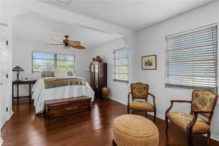 Bedroom with hardwood / wood-style flooring, multiple windows, arched walkways, and baseboards