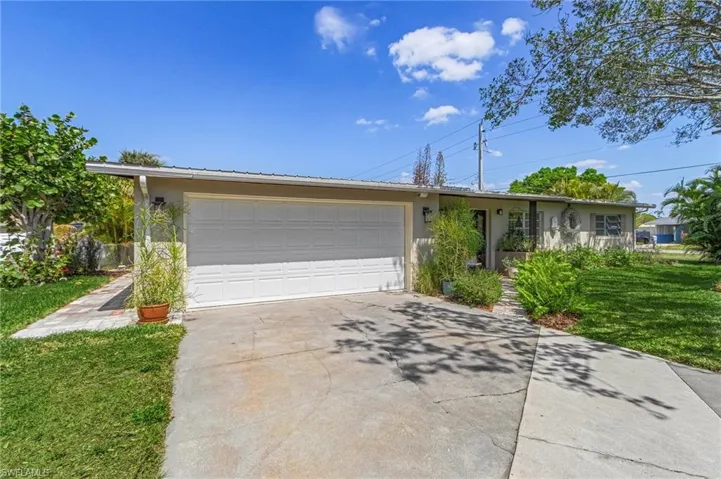 Single story home featuring stucco siding, metal roof, and a front lawn