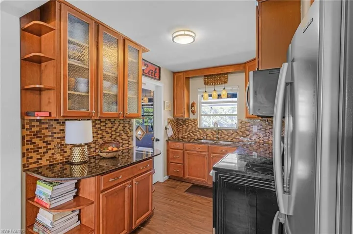 Kitchen featuring a sink, open shelves, wood finished floors, and stainless steel appliances