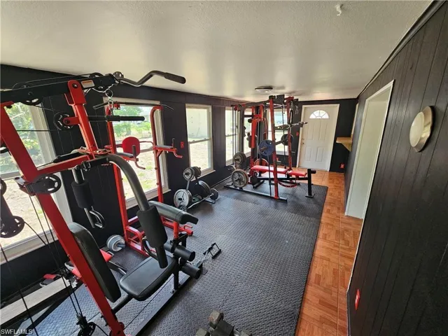 Interior space featuring black panelled walls, wood-patterned flooring, recessed lighting, and multiple windows with exterior exposure