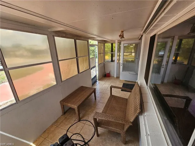 Enclosed porch featuring tile flooring, expansive window panels, and a screen door