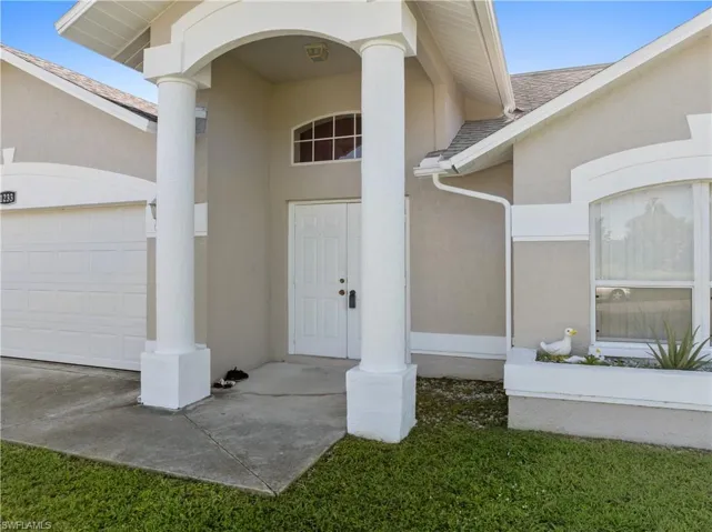 Entrance to property with stucco siding, a garage, and roof with shingles